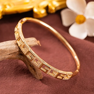 Detail eines vergoldeten griechischen Mäander-Armreifs mit Pavé-Zirkonia auf Holz
