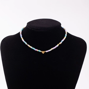 Detailed close-up of rainbow bead necklace featuring a gold heart pendant with letter B