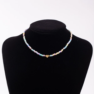 Detail shot of colorful macaron bead necklace featuring a gold heart pendant with letter C