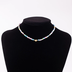 Detail showing rainbow seed bead necklace with gold heart pendant featuring engraved letter D