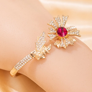 Détail du bracelet floral doré avec pierre centrale rouge et micro-diamants scintillants