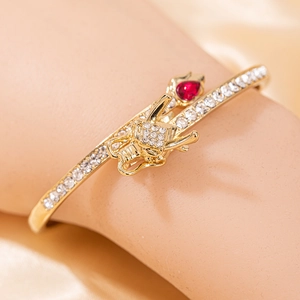 Gros plan d'un bracelet dragon doré orné d'une gemme rouge poire et de cristaux brillants