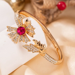 Bracelet rose doré élégant avec pierre rouge et strass pavés sur un support blanc