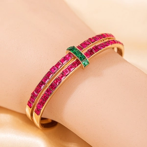 Vue détaillée du bracelet doré double rang avec pierres précieuses rouges et vertes