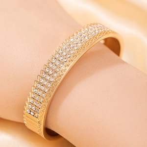 Détail macro du bracelet doré avec pavé de zircons et motifs de clé grecque ciselés