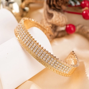 Bracelet jon jonc doré avec trois rangées de zircons et motif de clé grecque gravé