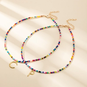 Ensemble de colliers en perles colorées avec pendentifs lettre dorés et ombre élégante