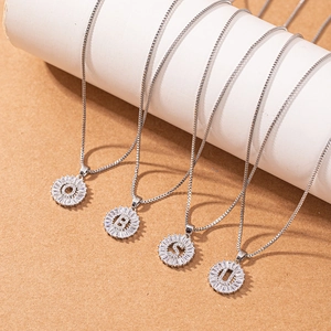 Silver alphabet letter pendant necklaces with baguette zircon round frame on white display