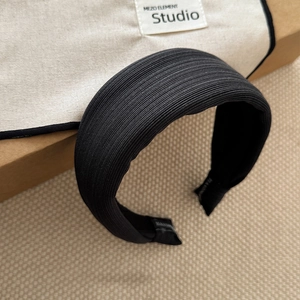 Close-up of black pleated fabric texture on a wide headband with fine knit detail