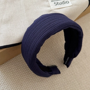 Close-up of dark blue striped headband with handmade tag on premium fabric texture