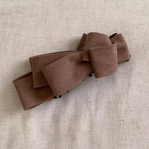 Detail view of multi-layered brown suede bow banana hair clip with secure black comb teeth