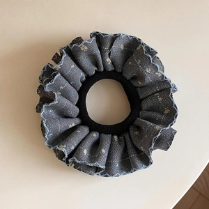 Gros plan d'un chouchou en denim à fleurs jaunes avec des bords brodés bleus