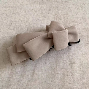 Detailed macro view of the soft beige faux suede fabric on the multi-layered bow hair clip