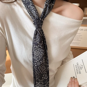 Gros plan d'un foulard étroit en soie à motif cachemire noir et blanc noué en cravate
