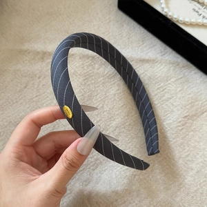 Detail of grey twill sponge headband featuring a gold Handmade oval metal logo