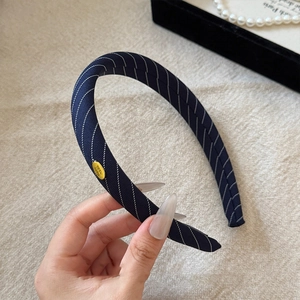 Detailed view of navy blue striped fabric headband with handmade gold emblem decoration
