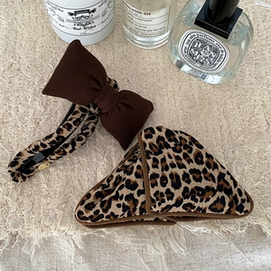 Leopard print bow hair clip and triangle claw set on neutral textured fabric background
