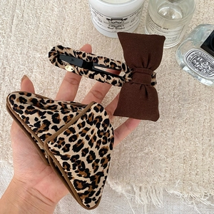 Leopard print hair clip with brown bow and matching pouch set on a white textured background
