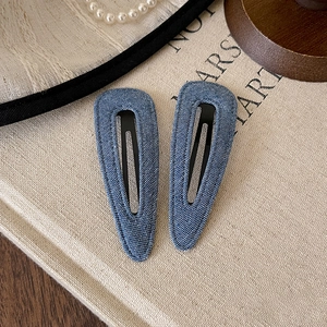 Detail of denim blue BB hair clips with classic fabric texture on vintage beige background