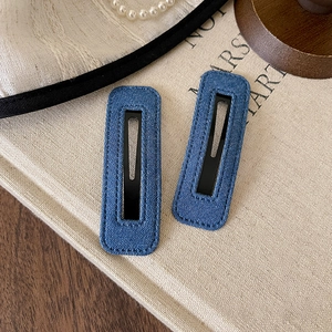 Close-up of navy blue denim BB hair clips with fine stitching and matte metal base
