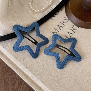 Detailed view of star-shaped denim hair clips with pearl jewelry on a vintage fabric