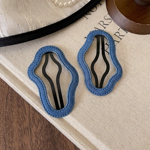 Close-up of wave-edge navy blue denim hair clips on a vintage book with pearls