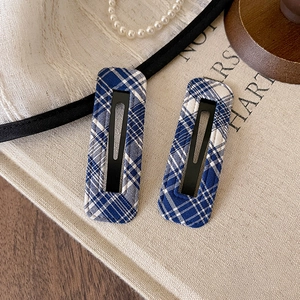 Detailed view of two vintage navy blue checkered fabric covered metal BB hair clips