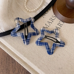 Detail of star-shaped hair clips with blue gingham fabric on beige canvas background
