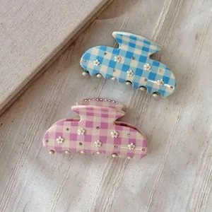 Detail of pink and blue checkered claw clips with floral patterns and rhinestones