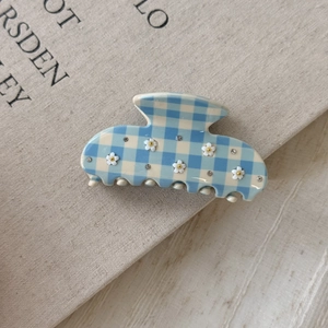 Detailed view of checkered blue acetate hair claw with 3D white flowers and crystals