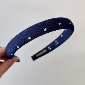 Detail of vintage denim headband with white heart pattern and handmade label
