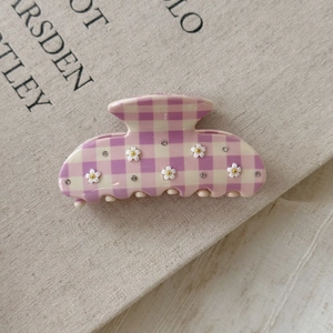 Close-up of pink checkered acetate hair claw clip with floral 3D decor and rhinestones