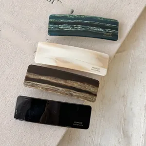 Detail of four handmade French style rectangular hair clips with marble and shell textures