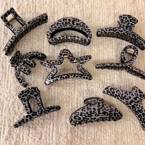 Set of 8 vintage grey leopard print hair claws in various shapes on beige fabric background