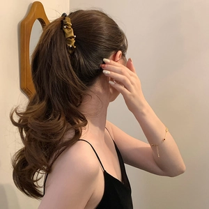 Vintage gold pleated silk banana hair clip with pearls worn in an elegant ponytail