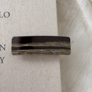 Detail of tortoiseshell acetate hair clip with gold France Handmade logo on linen background