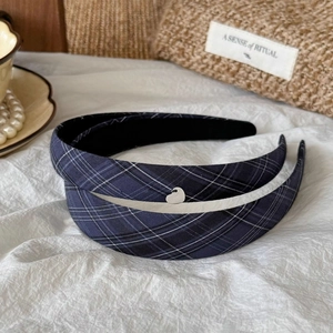 Detail of navy plaid headbands with heart charms on textured white fabric