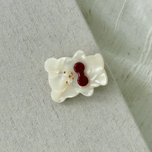 Makroaufnahme einer Acetat-Bären-Haarspange mit roter Schleife auf Leinenhintergrund