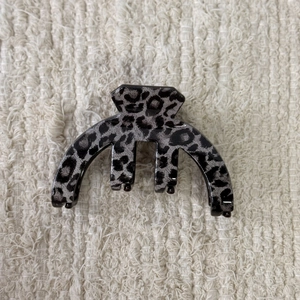 Detail view of grey leopard print hair claw clip on neutral textured fabric background