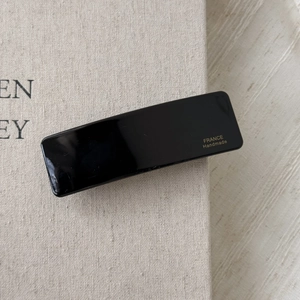 Detail of black rectangular barrette with gold France Handmade lettering on linen