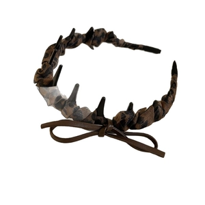 Serre-tête léopard avec clous noirs et nœud en cuir marron sur fond blanc pur