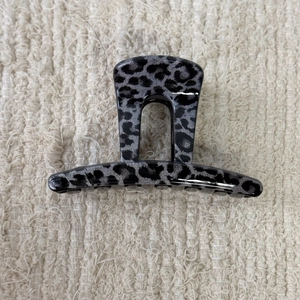 Detail view of grey leopard print hair claw clip on white textured background
