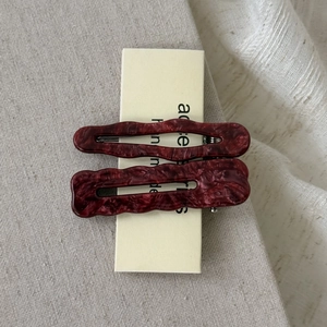 Close-up of a pair of wavy marble wine red acetate hair clips on a display card