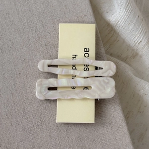 Detail of wavy acetate hair clips with pearl white marble texture on display card
