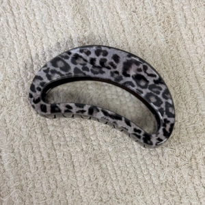 Detail view of a grey leopard print hair claw clip on a soft textured background