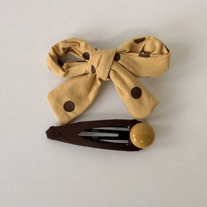 Close-up of yellow polka dot bow hair clip and brown hairpin with bead decoration