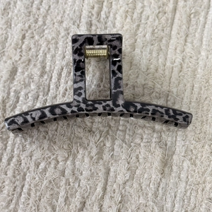 Detail of grey leopard marble hair claw clip with golden spring on beige fabric