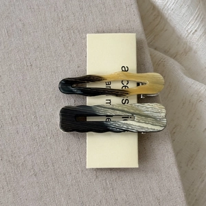 Close-up of tortoise shell and gray marble acetate hair clips on beige linen background