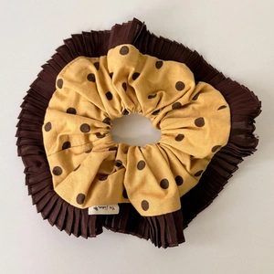 Macro detail of yellow polka dot and brown chiffon scrunchie with designer label