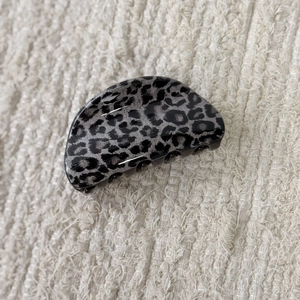 Detail view of a vintage leopard print hair claw clip in grey and black resin on a soft fabric